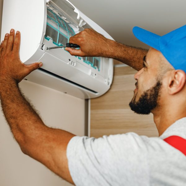 Professional repairman installing air conditioner in a room Professional repairman installing air conditioner in a room