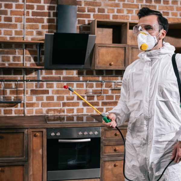 side view of pest control worker standing with sprayer in kitchen side view of pest control worker standing with sprayer in kitchen